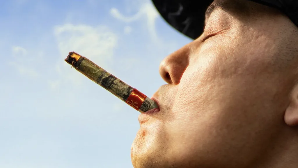 Asian man smoking a joint in the sun.
