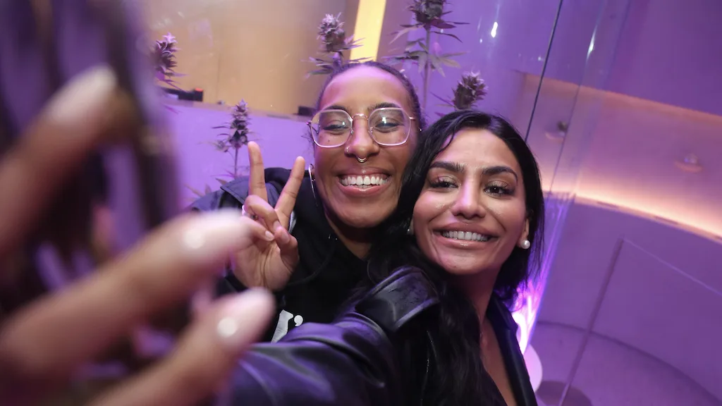 Two female friends taking a selfie at a retro weed dispensary.