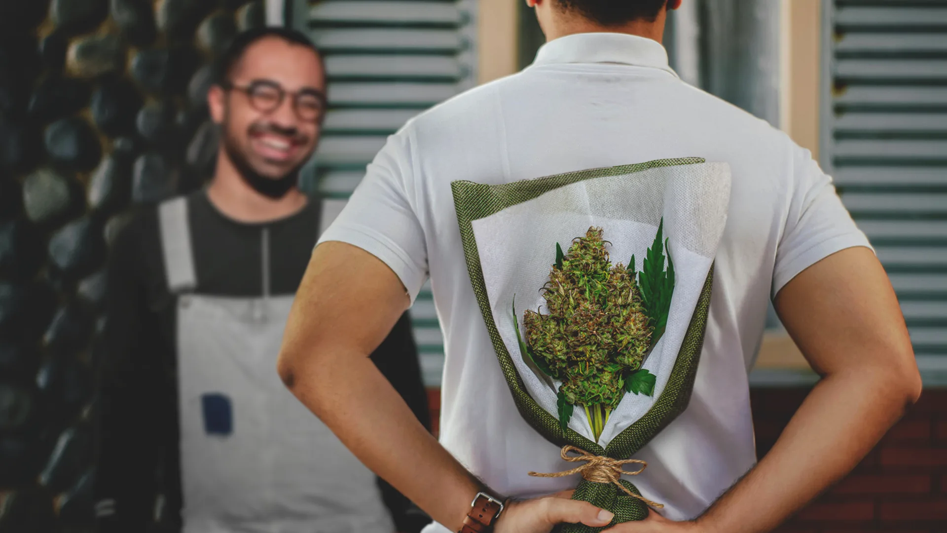 Man holding cannabis bud behind back about to gift like flowers.