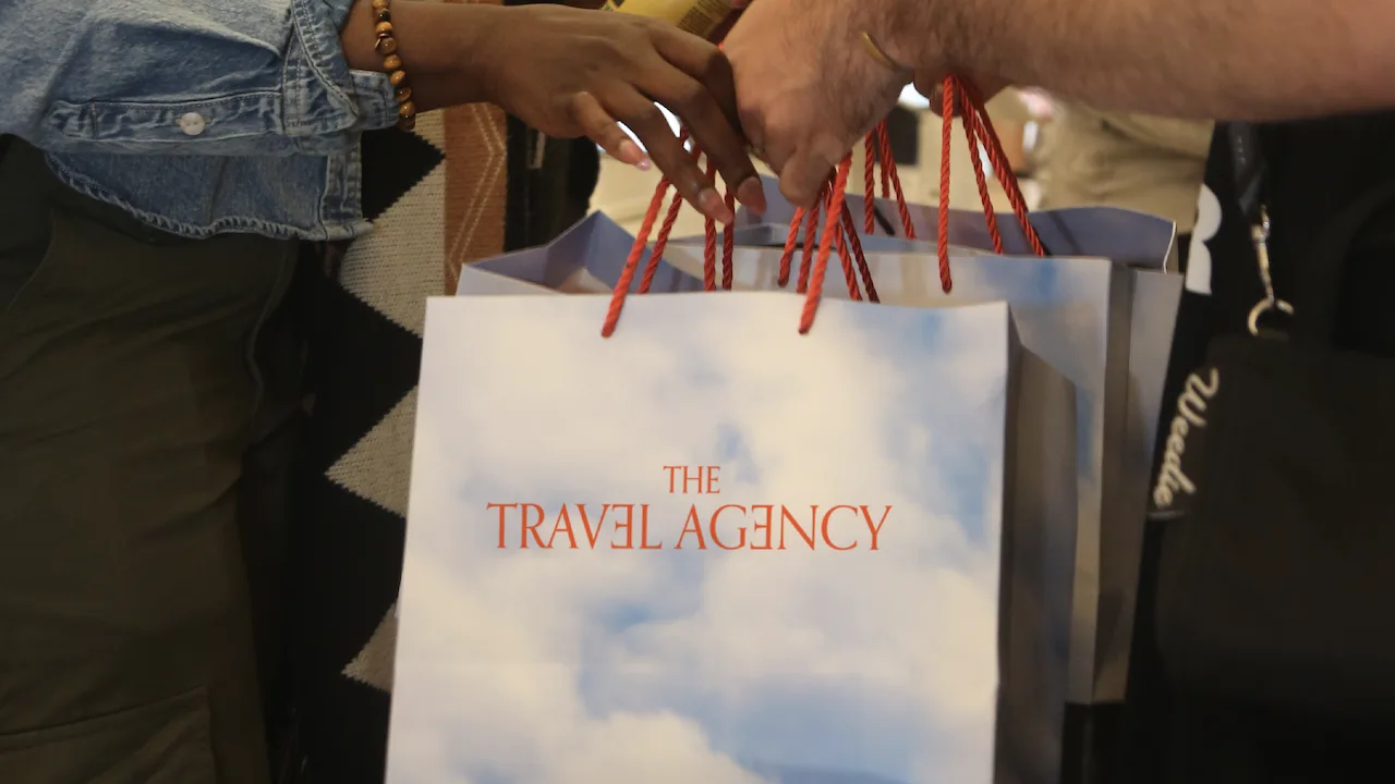 Two people exchanging shoppings bags at The Travel Agency.