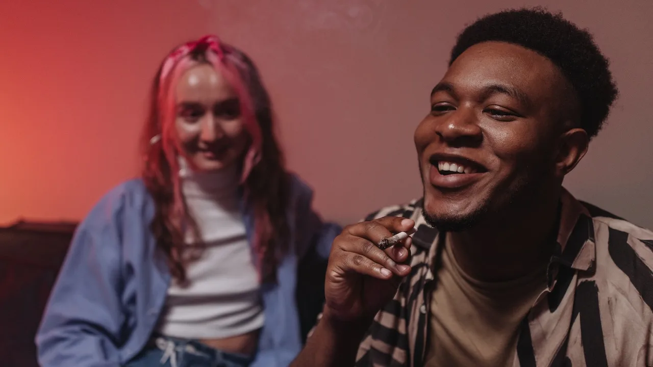 Two friends happily sharing a joint together.