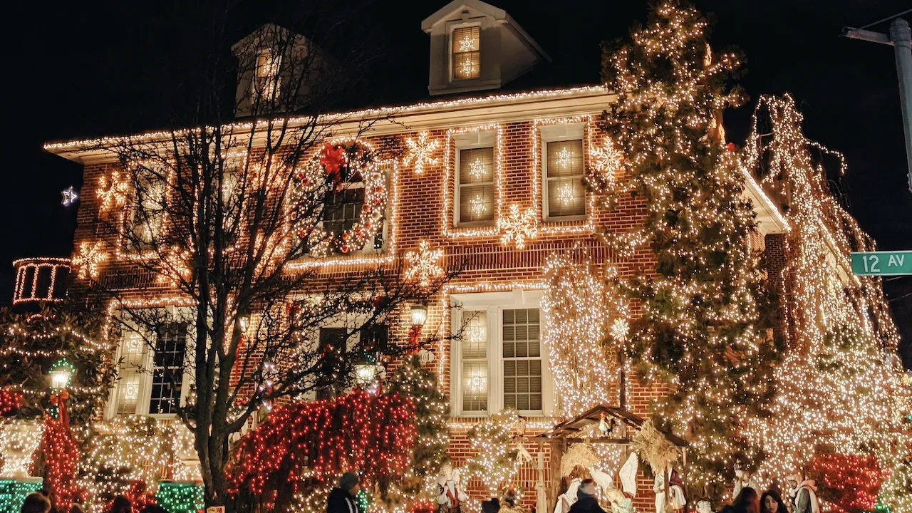 Classic red two-story American home with many white Christmas lights.