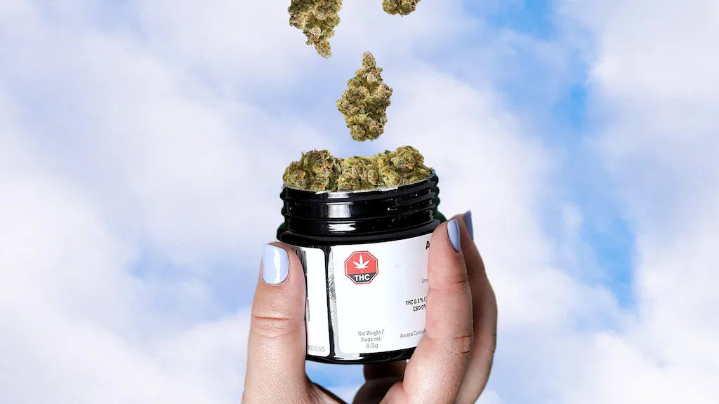 Woman holding a black jar of cannabis.