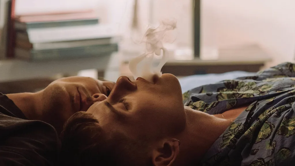 Two men blowing weed clouds.