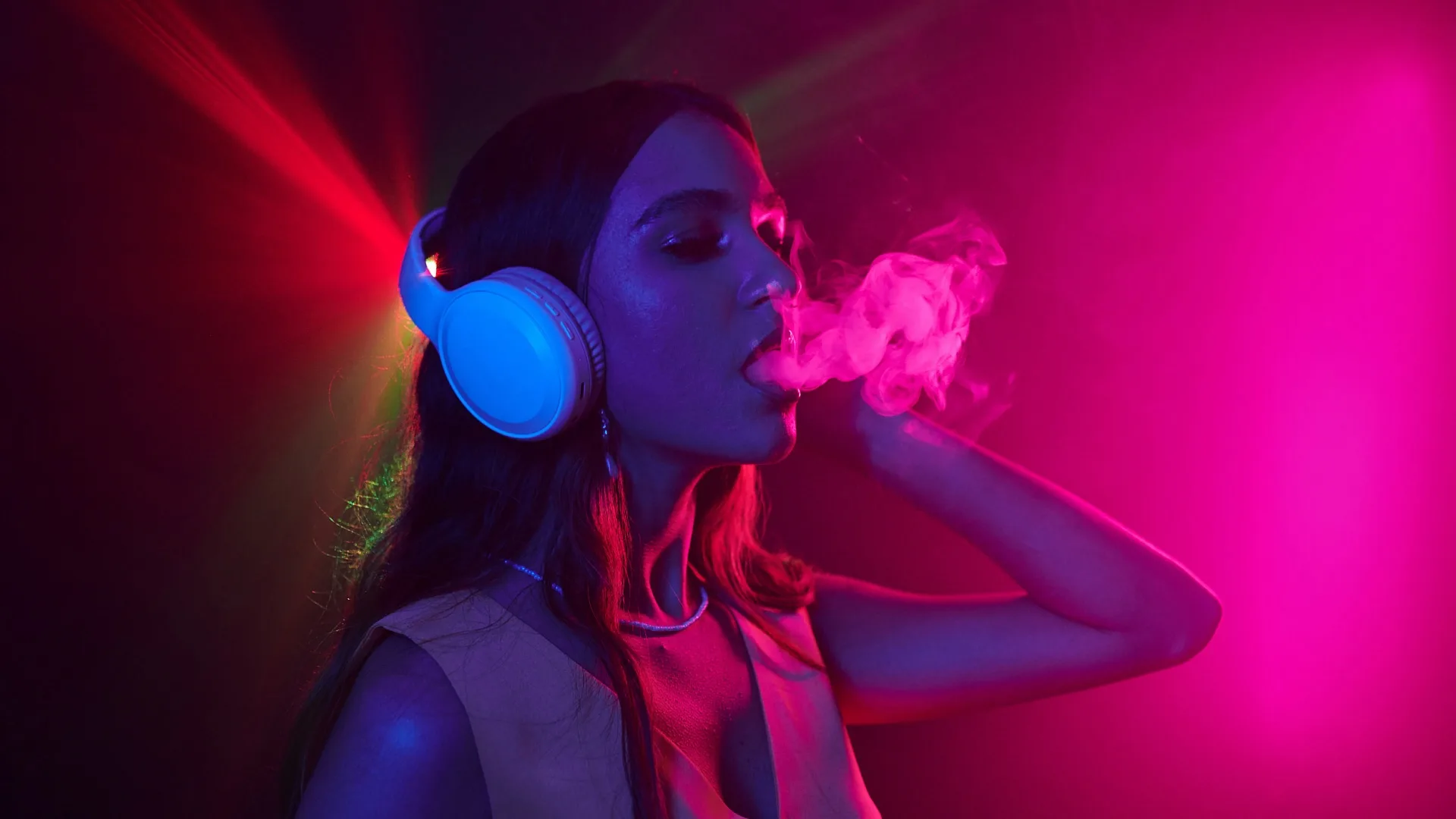 Stoner woman in headphones, blowing out a cloud of smoke.
