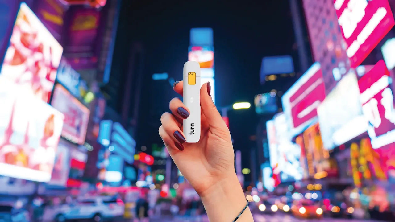 Female hand holding a Turn disposable vape in Time's Square NYC.
