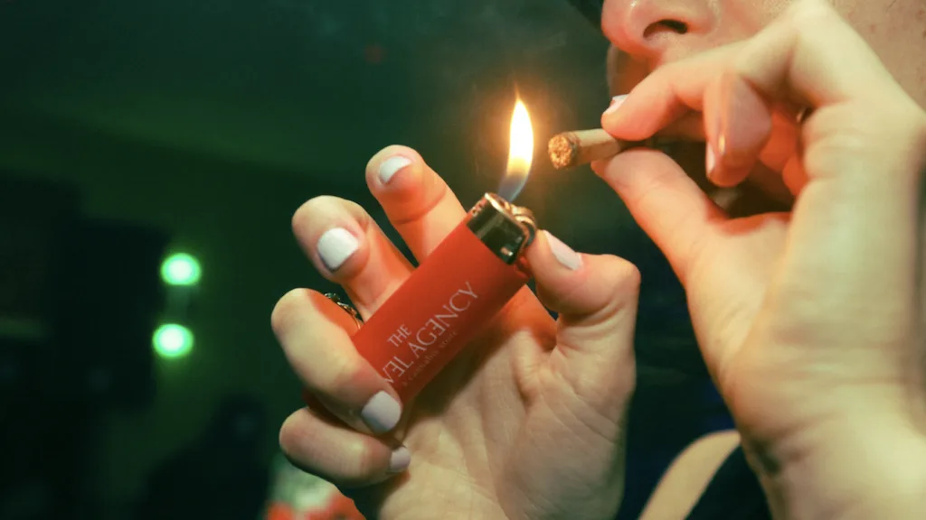 Woman lighting a joint with a red lighter.